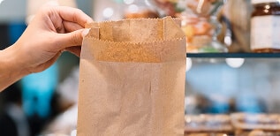 Shop assistant giving croissant bag